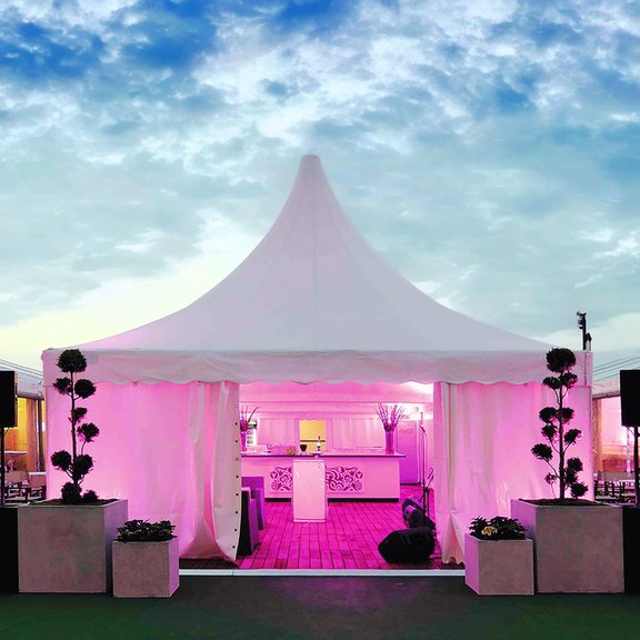 Frontal view of a RÖDER 6 x 6 m pagoda tent with interior lighting and evening sky