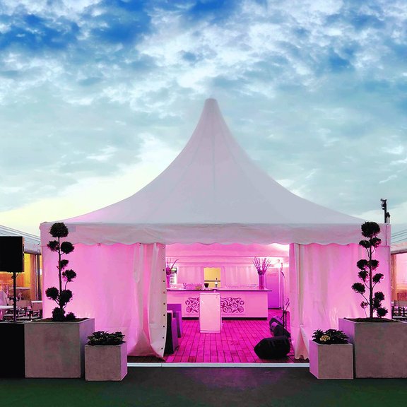 Frontal view of a RÖDER 6 x 6 m pagoda tent with interior lighting and evening sky