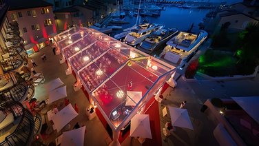 A view from above of an exclusive event tent with a transparent roof in a marina