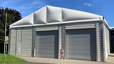 Front view of a vehicle shed with trapezoidal sheet metal façade and thermal roof tarpaulin