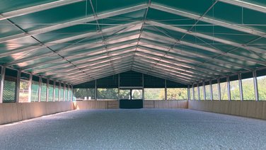 Interior view of an indoor riding arena from RÖDER floor with sand and wooden band