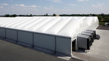 Side view of a multi-aisle warehouse with four loading ramps and a thermal roof tarpaulin from RÖDER