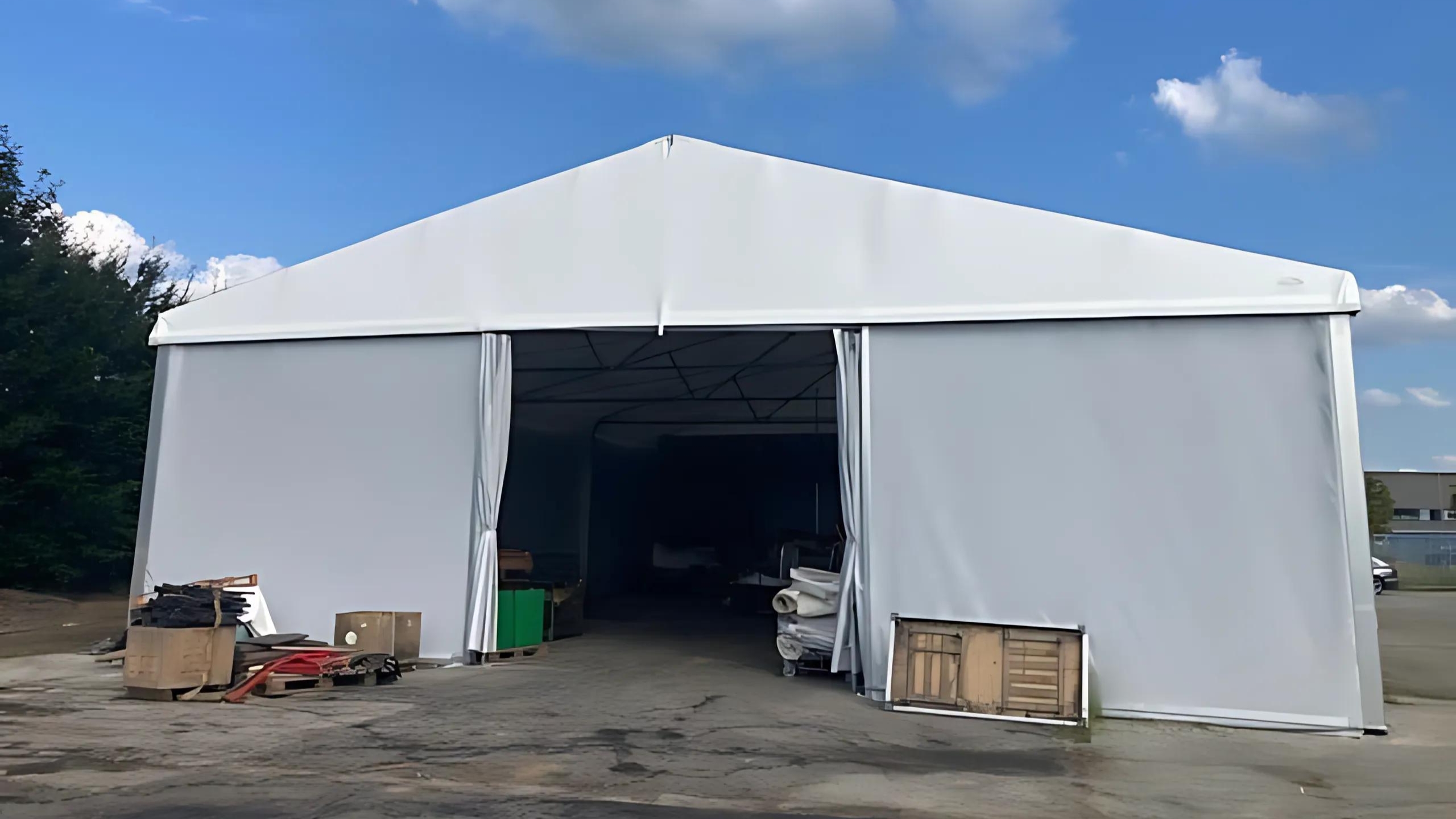 Gable side of a tent hall with a sliding tarpaulin gate in the centre Giebelseite_einer_Zelthalle_mit_Planenschiebetor_in_der_Mitte.jpg